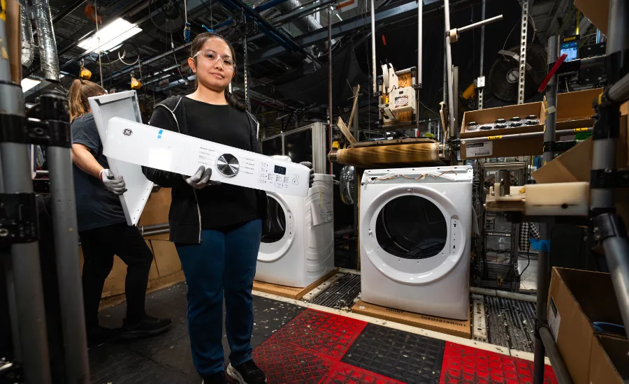 Woman at manufacturing plant holds up her work product
