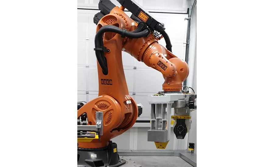 KUKA industrial robot using end-of-arm tooling to handle heavy engine component in automated manufacturing cell