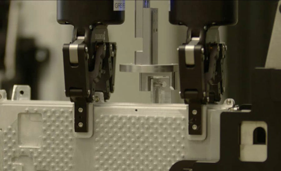 Robotic grippers handling a component during an automated manufacturing process.