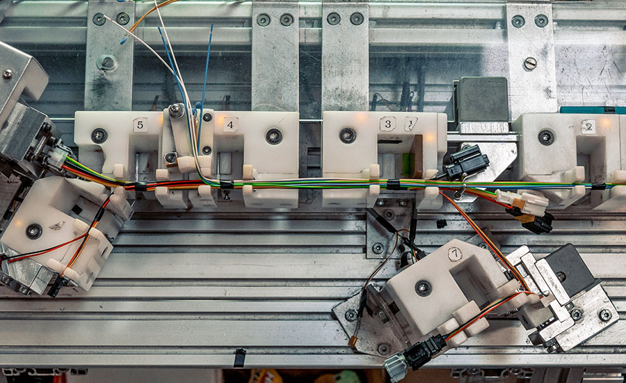 Top-down view of a wire harness assembly fixture with routing blocks, connectors, clamps, and cable harnesses positioned for manufacturing and assembly.
