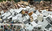 Pile of discarded appliances, scrap metal, wood debris, and plastic waste at a recycling and waste processing facility.