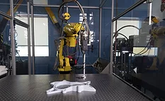 Industrial robot performing automated 3D scanning and inspection of a manufactured component on a precision measurement table.