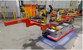 Autonomous mobile robot transporting a welding fixture and tooling assembly through an automotive manufacturing facility for flexible production operations.