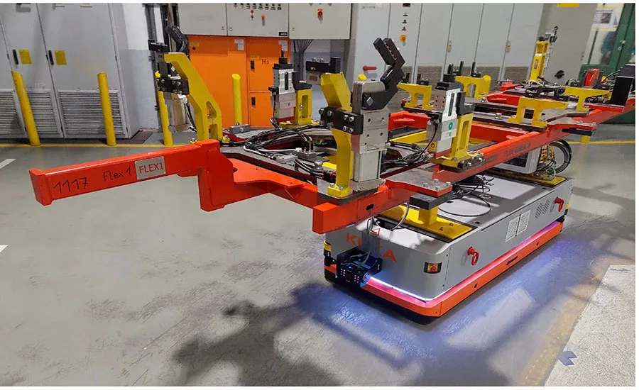 Autonomous mobile robot transporting a welding fixture and tooling assembly through an automotive manufacturing facility for flexible production operations.