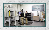 Process Development Center Engineers operating a materials testing system in a process development center, using automated testing equipment to evaluate product performance and manufacturing processes.