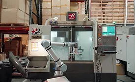 Collaborative robot loading parts into a CNC machining center.