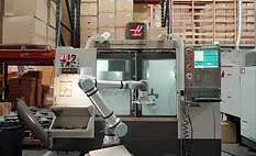 Collaborative robot loading parts into a CNC machining center.