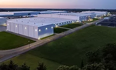 Aerial view of a large industrial warehouse and distribution complex at dusk.