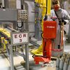 Ordnance technicians use a lift-assist device to aid in the processing of 105-millimeter projectiles