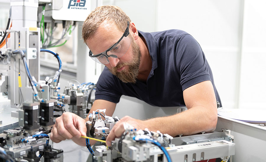 technician fine-tunes a handling mechanism for an automated assembly system